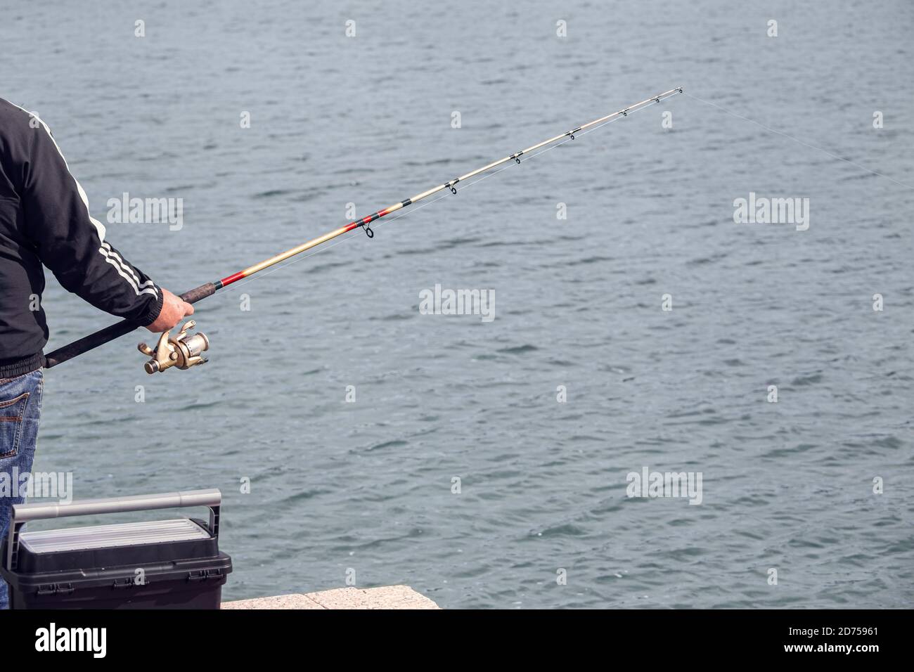 Fischer stehen am Rande des Docks mit Angelrute in der Nähe des Meeres an sonnigen Tag. Speicherplatz kopieren Stockfoto