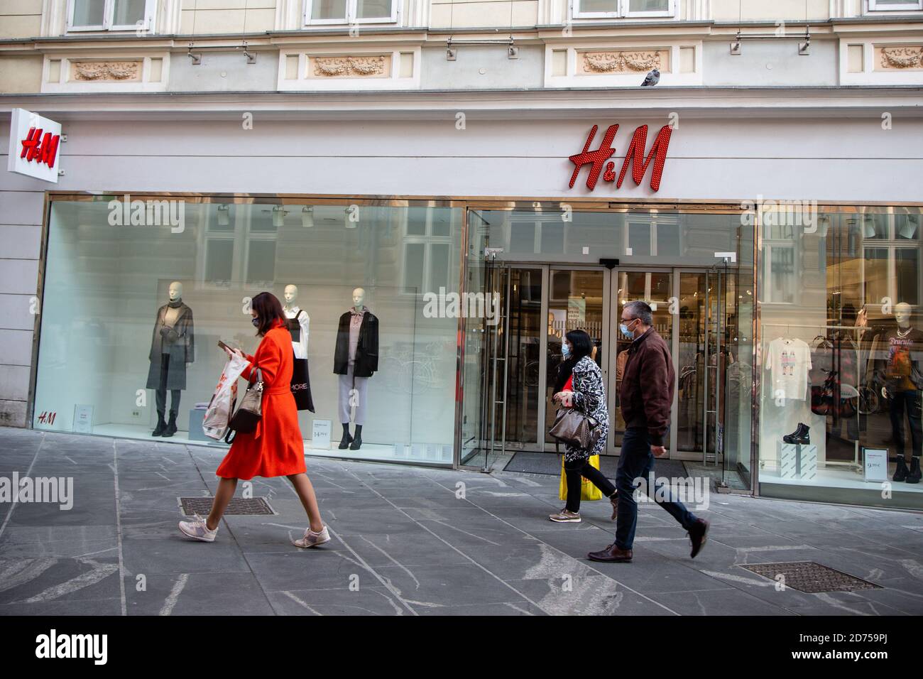 Menschen mit Gesichtsmasken gehen am schwedischen multinationalen  Bekleidungseinzelhandel H&M Store in Ljubljana vorbei, nachdem Slowenien  eine Epidemie erneut deklariert hat.als täglich neue covid-19 Fälle  überstanden wurden, erklärten 20 Prozent ...