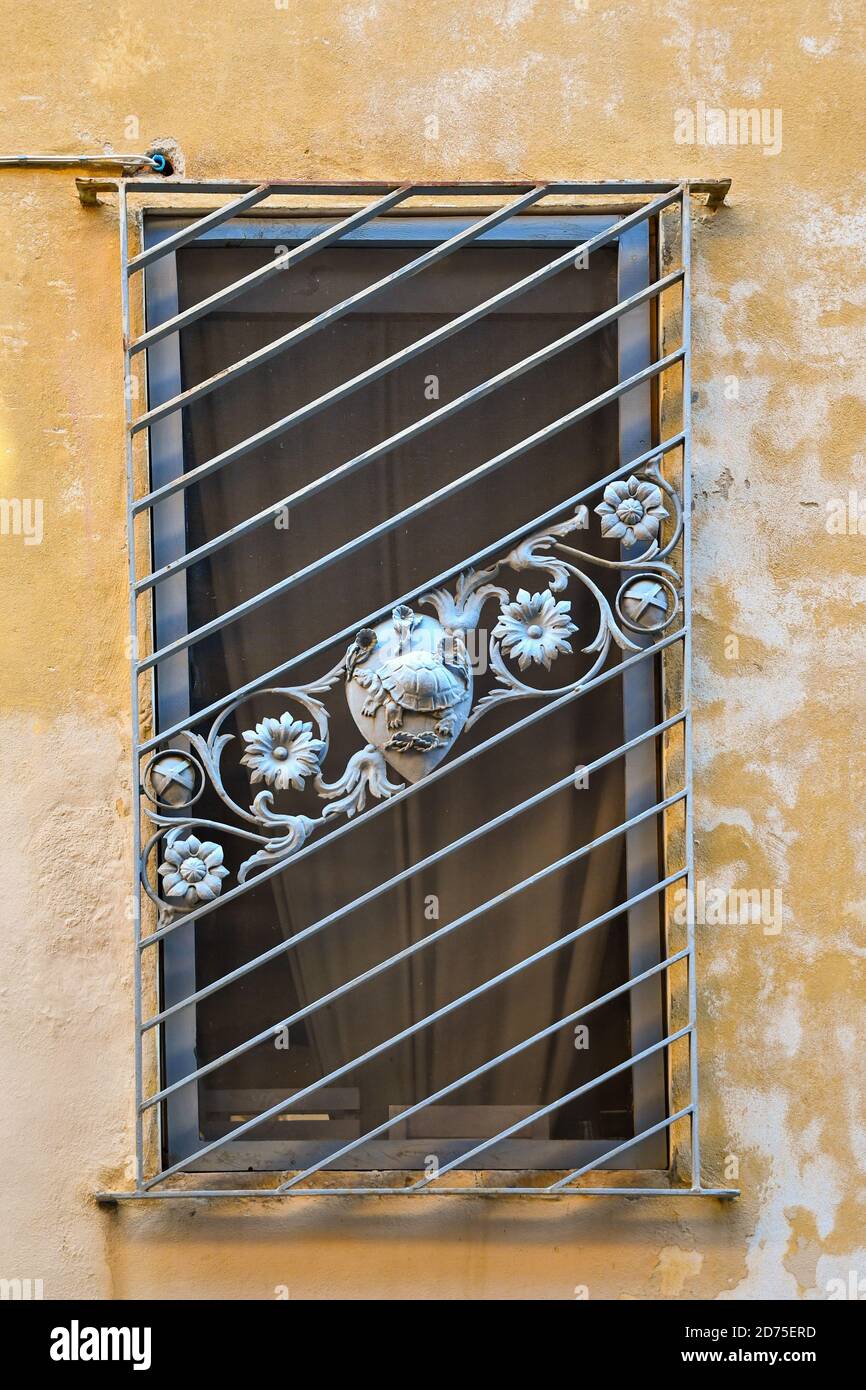 Nahaufnahme eines Fensters, das von einem Metallgitter mit den Symbolen der Contrada della Tartuca (Handel der Schildkröte), Siena, Toskana, Italien, geschlossen wird Stockfoto