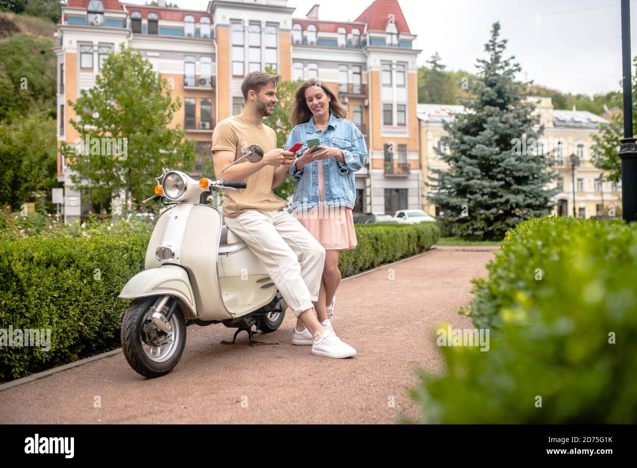 Mann und Frau mit Smartphones während einer Scooter-Reise Stockfoto
