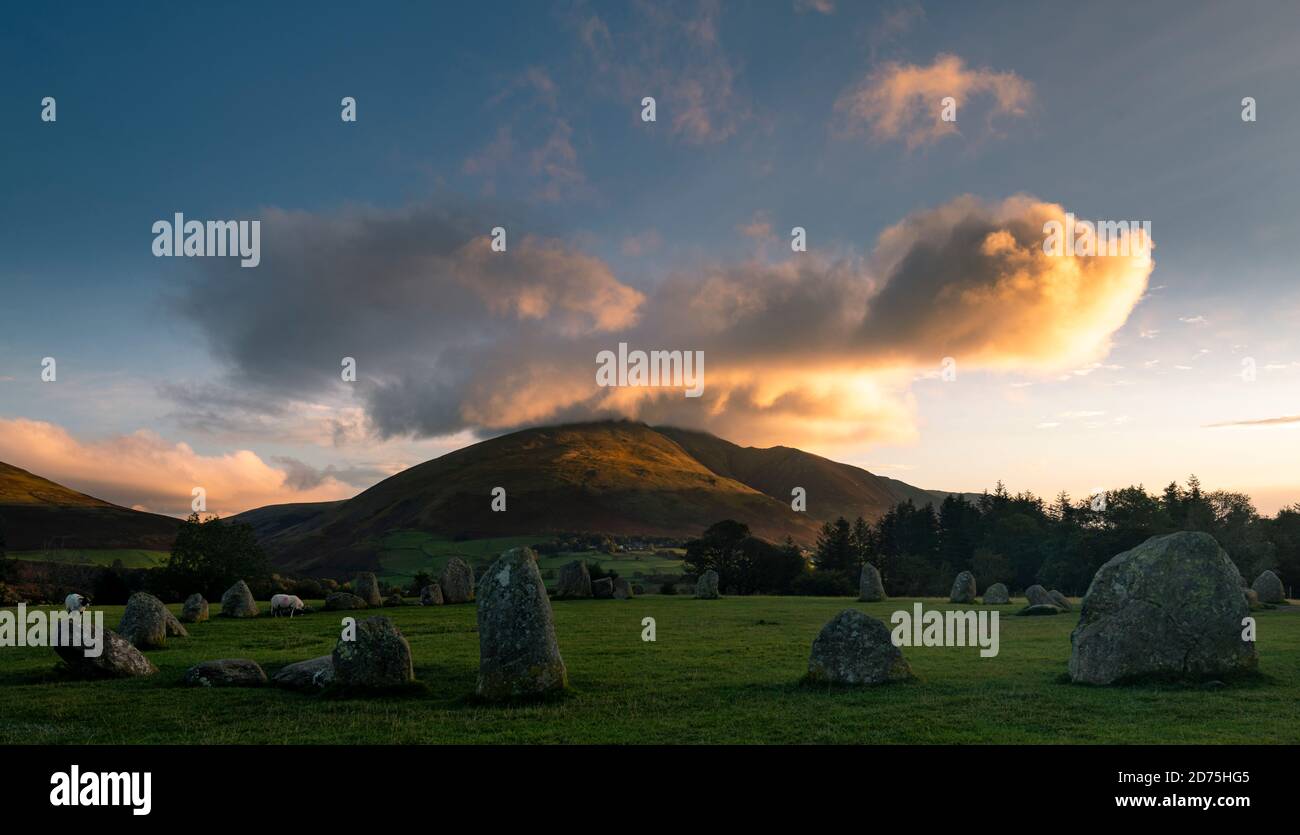 Erstes Licht, das den Gipfel von Blencathra und die Wolken erhellt Als die Sonne mit Castlerigg Steinkreis aufgeht Im Vordergrund Stockfoto