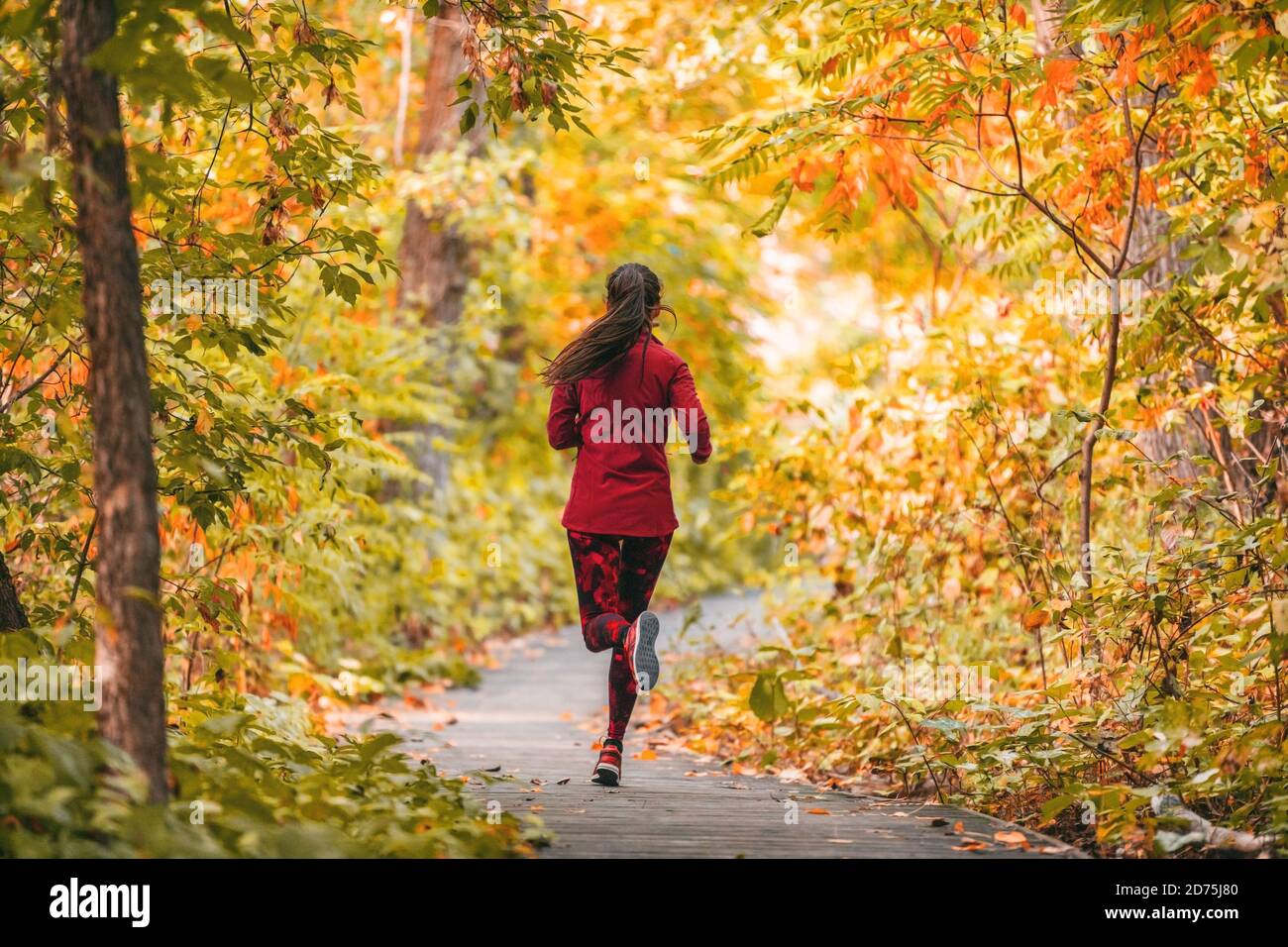 Laufen Frau Joggen im Freien Herbst Laub Natur Hintergrund im Wald. Trailrunner Läufer Training Cardio im Freien, orange Farben Stockfoto