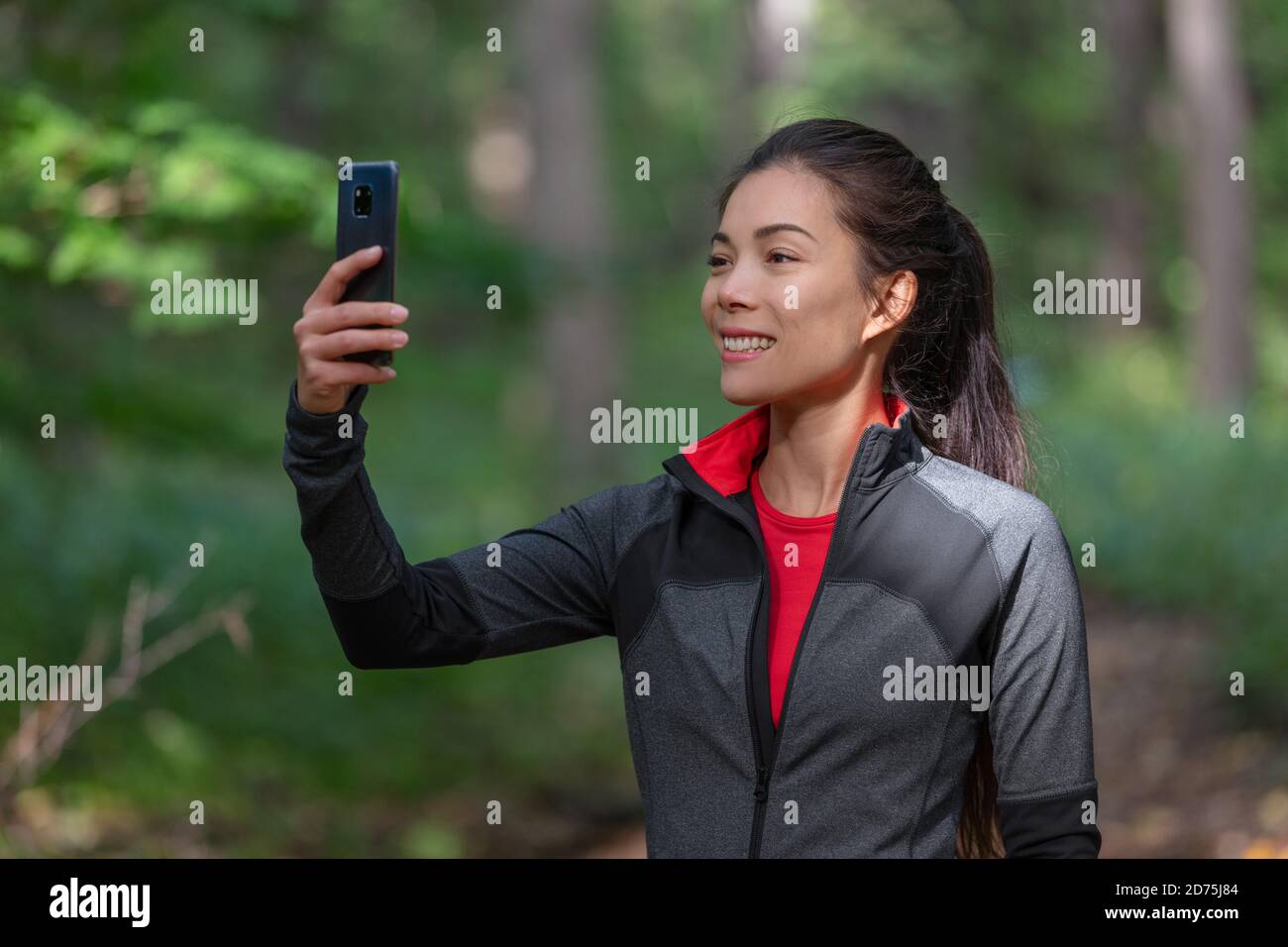 Handy aktive Frau fotografieren mit Handy draußen auf Wald Natur Spaziergang während Cardio-Aktivität halten Smartphone Stockfoto