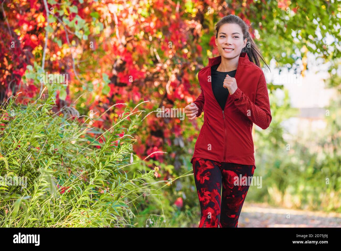 Gesunde aktive Lebensweise Laufen asiatische junge Frau Cardio-Training auf Stadtpark laufen Joggen im Freien im Herbst Blätter Stockfoto