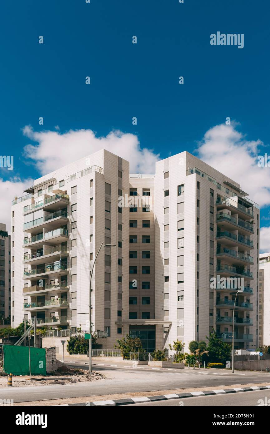 Wohngebäude im neuen Stadtteil Rosh Haayin, Israel. Neues Gebäude. 10-stöckiges Haus mit einer Straße in der Nähe und einem blauen Himmel mit Wolken Stockfoto