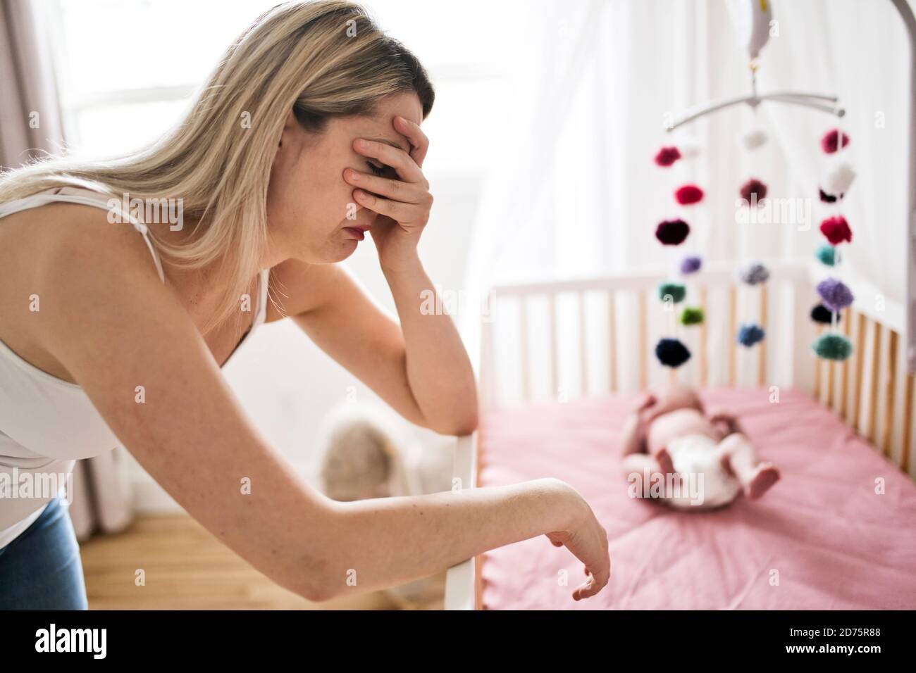 Mutter leidet an postnatalen Depressionen in der Nähe von Krippe mit niedlichen Baby Zu Hause Stockfoto