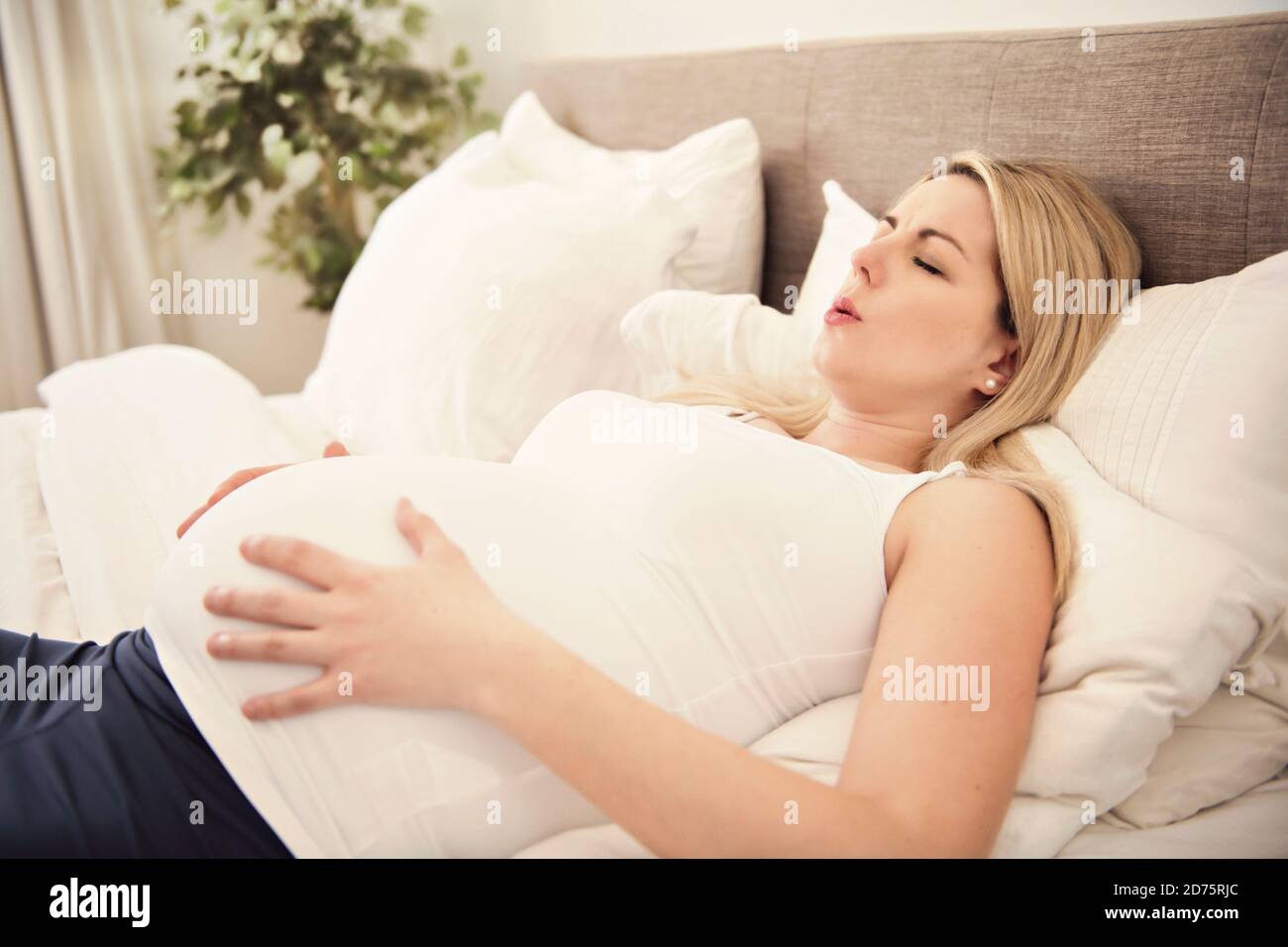 Schwangere Frau auf dem Bett zu Hause mit Kontraktionen Stockfoto