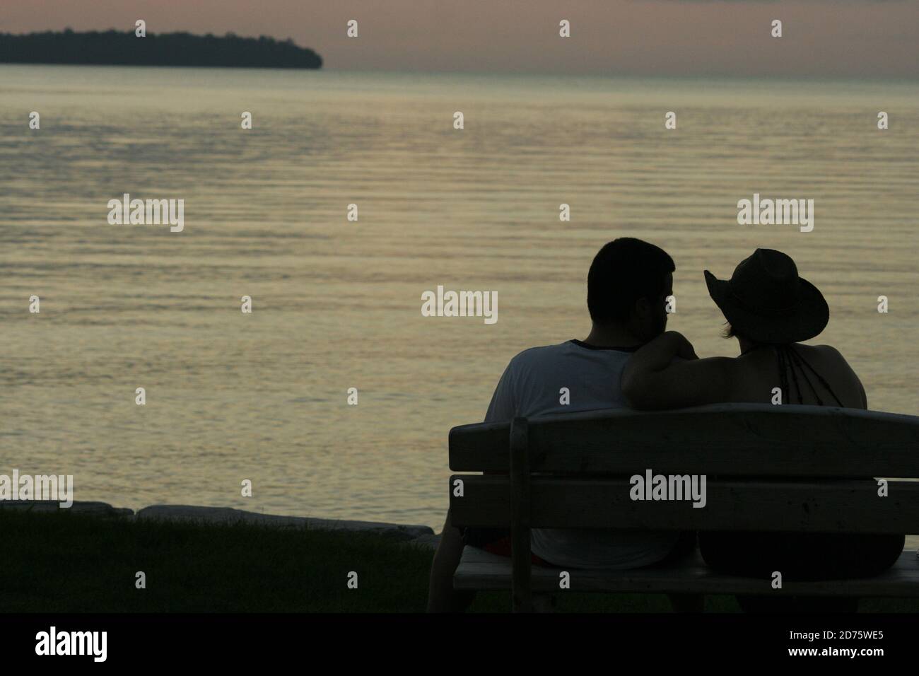 Pärchen sitzt am Wasser bei Sundown Stockfoto