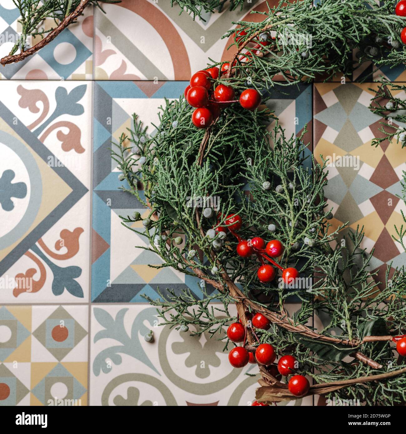 Weihnachten Kranz Detail der immergrünen, roten Beeren und gold Rentier auf Retro geometrische Fliesen. Nandian Netzwerk, grüner Zweig und rustikalen Krone. Fla Stockfoto