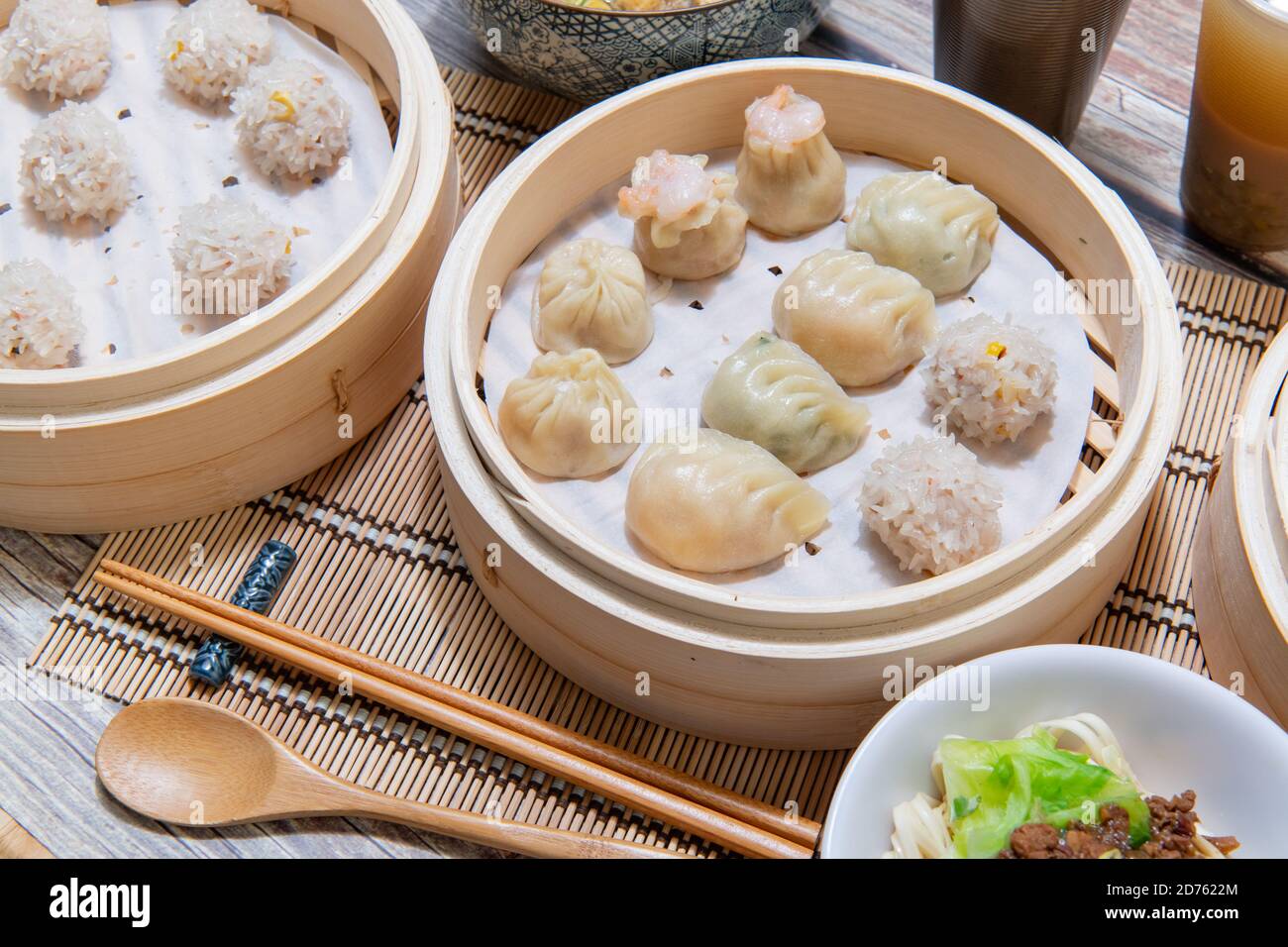 Gedämpfte Xiaolongbao und Shaomai in einem traditionellen Dampfkorb serviert Stockfoto