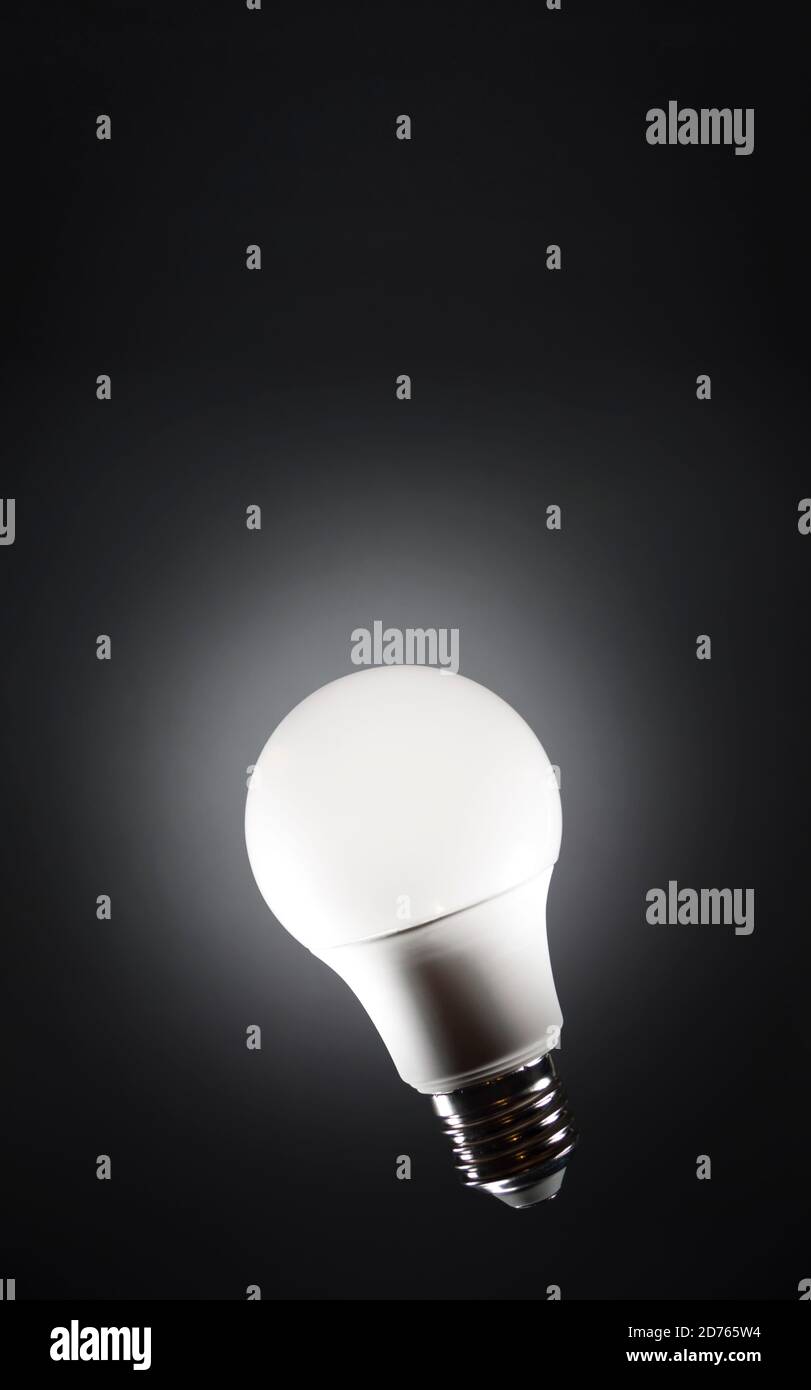 Glühbirne schwimmt in dunklen leeren schwarzen Raum und leuchtet. LED-Anzeige für Energiesparmodus. Stockfoto