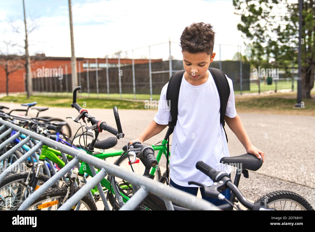 Boy Reiten Fahrrad trägt einen Helm draußen auf dem Schulhof Stockfoto