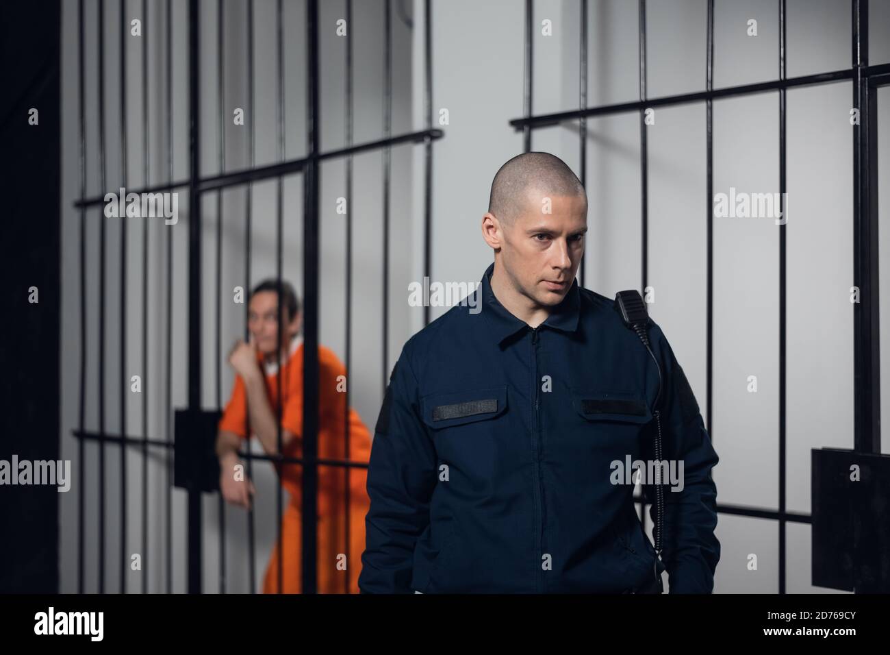 Ein uniformierter Aufseher in einem asiatischen Gefängnis macht abends mit Gefangenen eine Tour durch die Zellen. Stockfoto