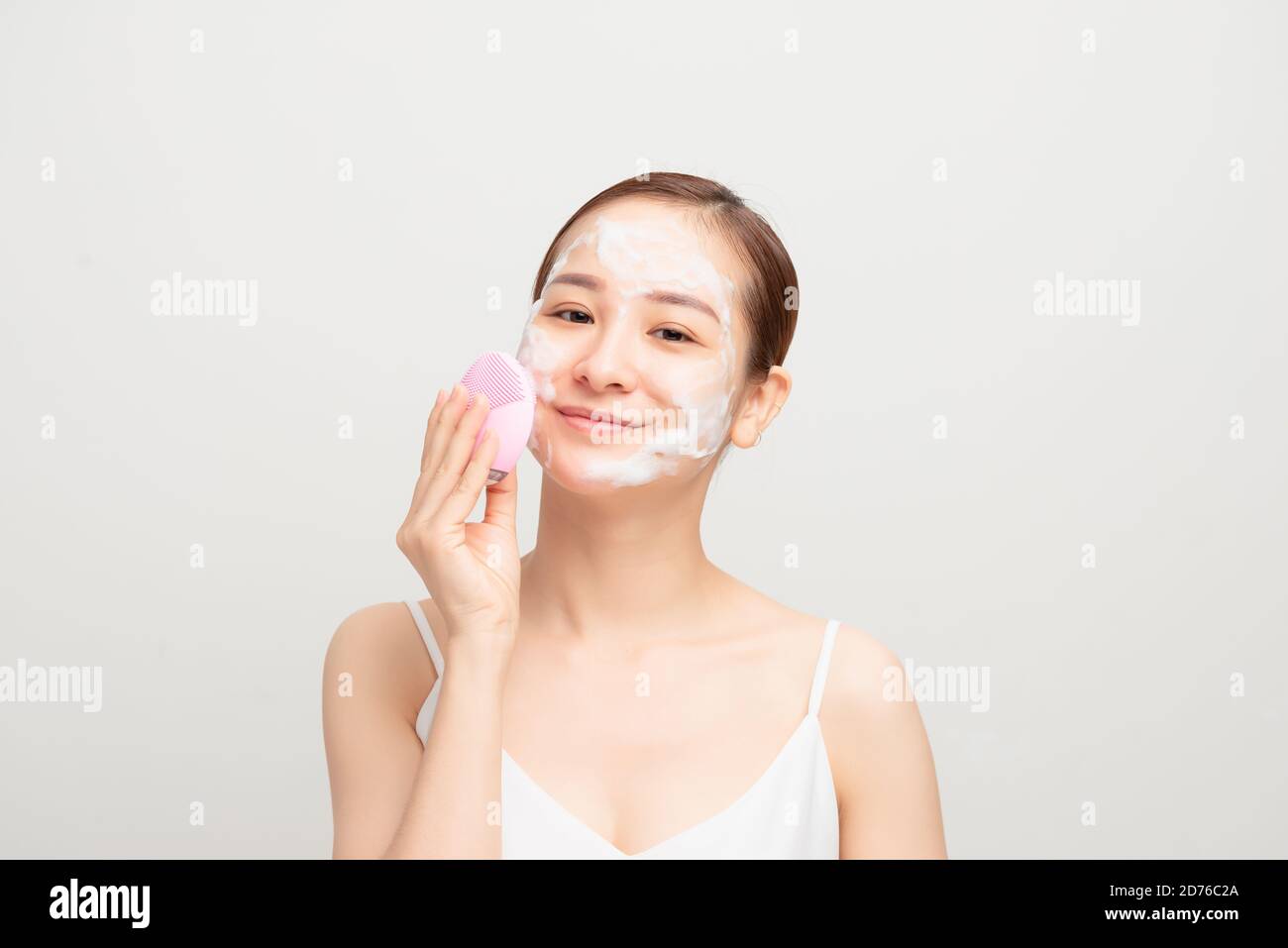 Junge Frau mit Gesichtsreinigungsbürste auf weißem Hintergrund, Nahaufnahme. Waschzubehör Stockfoto