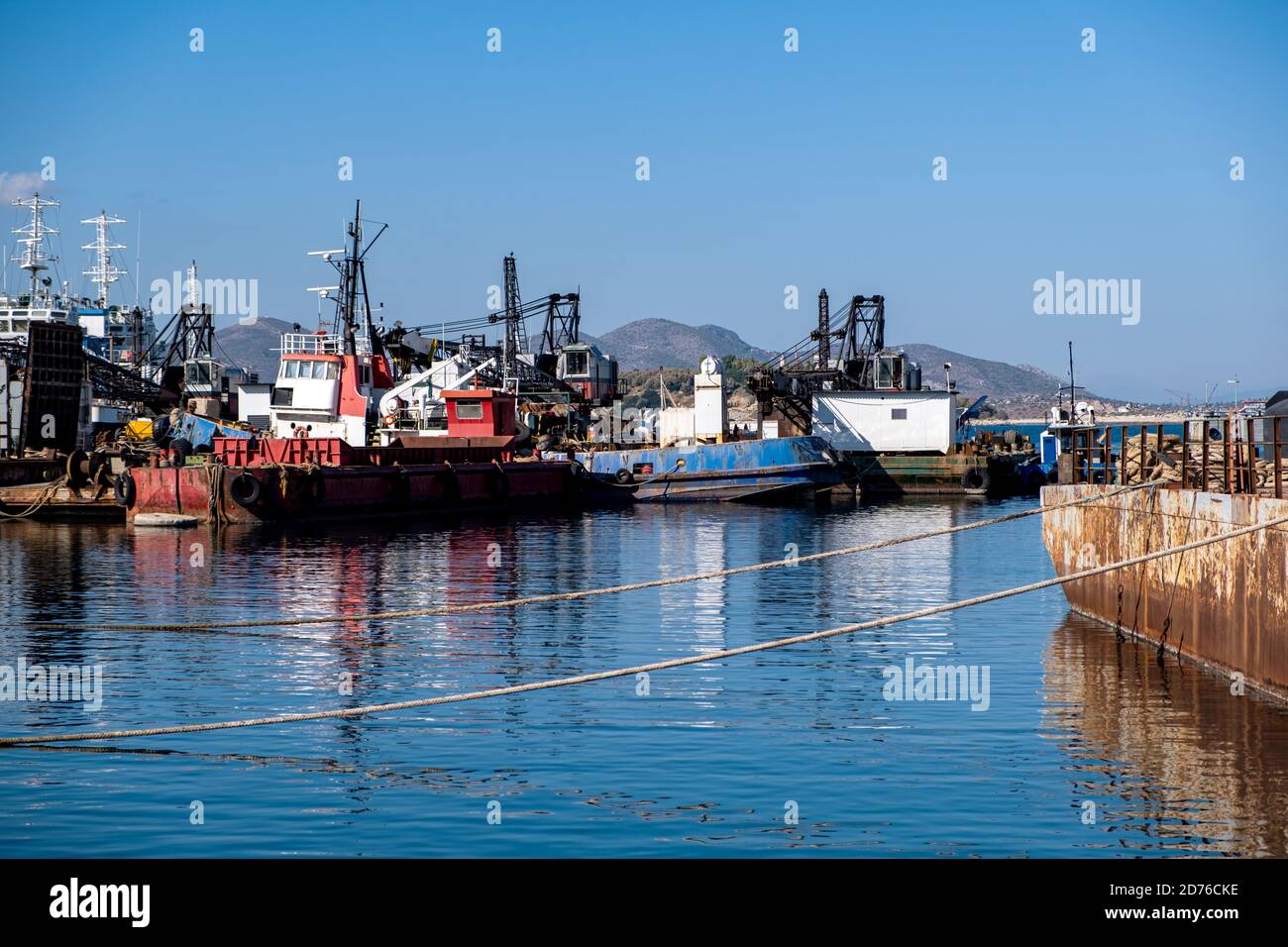 Industrieschiffe und Boote, die im alten Hafen von Drapetsona Piraeus festgemacht sind, Griechenland, blauer Himmel und Meer, sonniger Tag. Stockfoto