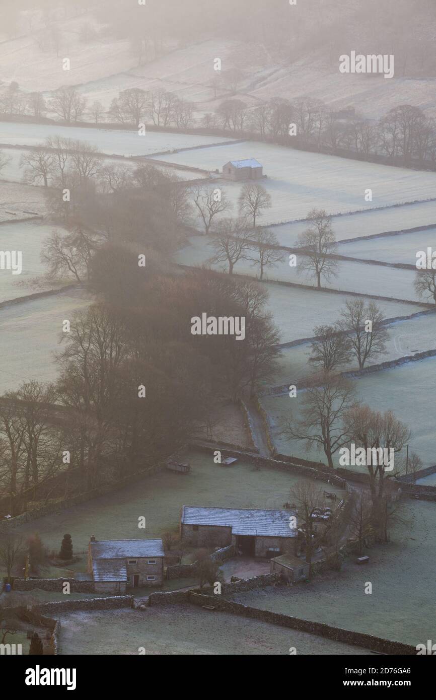 Blick hinunter auf eine typische Yorkshire Dales Valley Farm in Winter mit Bauernhöfen und frostbedeckten Feldern Stockfoto