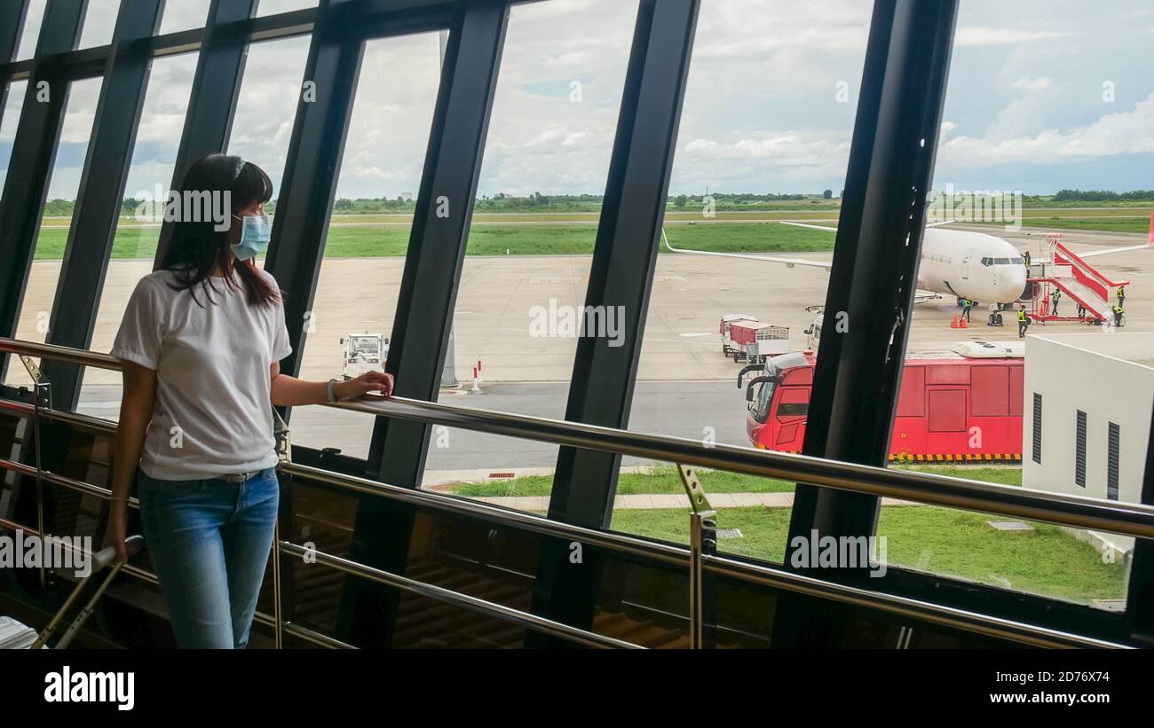 Asian Tourist mit Trolley Gepäck, trägt hygienische Maske, um Pandemie während der Reise am Flughafen-Terminal zu verhindern. Neue normale nach Coronavirus covid-19 Stockfoto