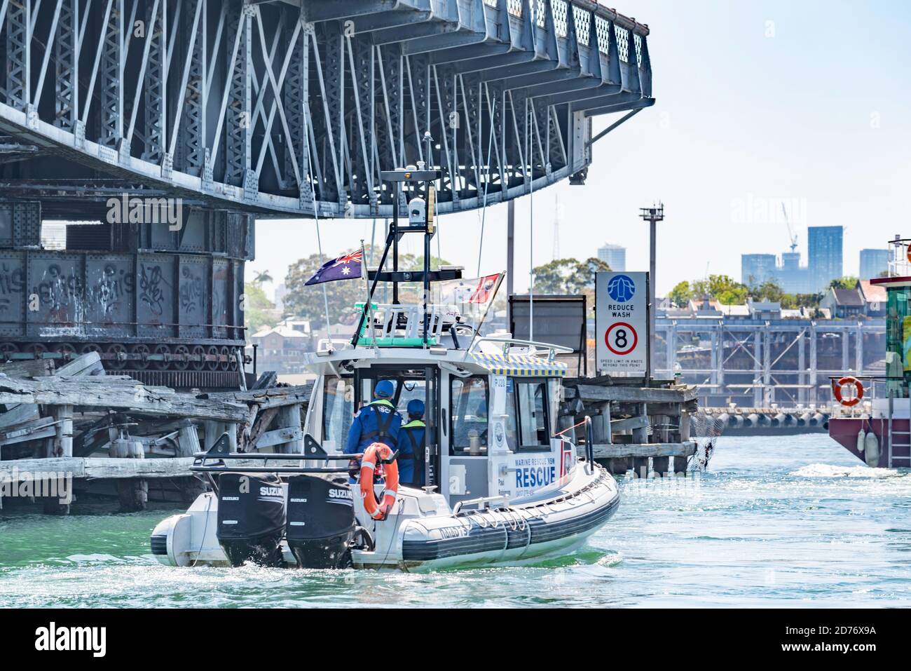 Ein ehrenamtliches maritimes Rettungsboot fährt neben der dauerhaft geöffneten, historischen 1903 Glebe Island Swing Bridge im Sydney Harbour, Australien Stockfoto