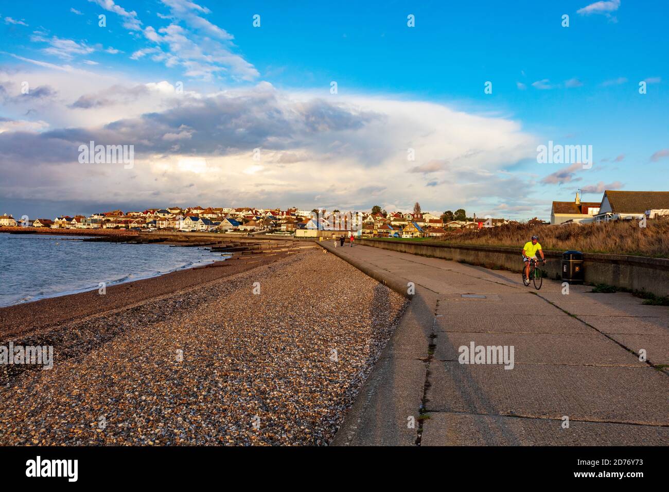 Die Sonne am späten Nachmittag im Herbst bringt Radfahrer und Wanderer auf die Promenade von Hampton, Herne Bay. Oben ist eine interessante Wolkenformation. Kent, Großbritannien Stockfoto