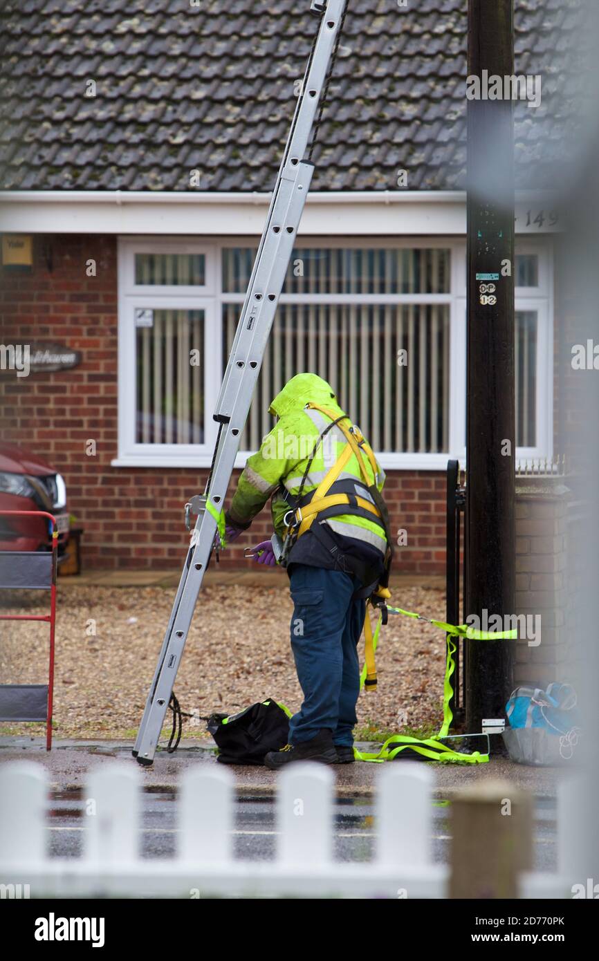 Ein offener Telekommunikationsingenieur bei der Arbeit auf einer Leiter trägt er die richtige PSA für die Arbeit in der Hand und erfüllt gleichzeitig die H&S-Vorschriften. Stockfoto