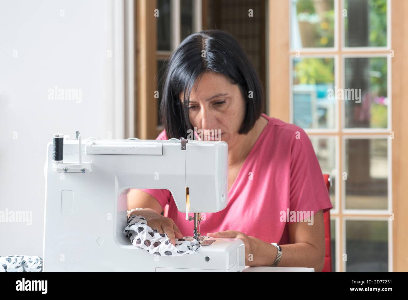 Frau, die selbstgemachte Gesichtsmasken auf Nähmaschine macht, Stockfoto
