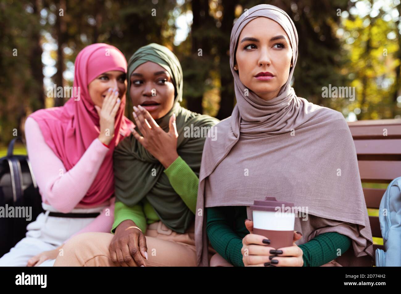 Muslim Ladies Whispering Hinter Zurück Von Weiblich Freund Sitzen Im Freien Stockfoto