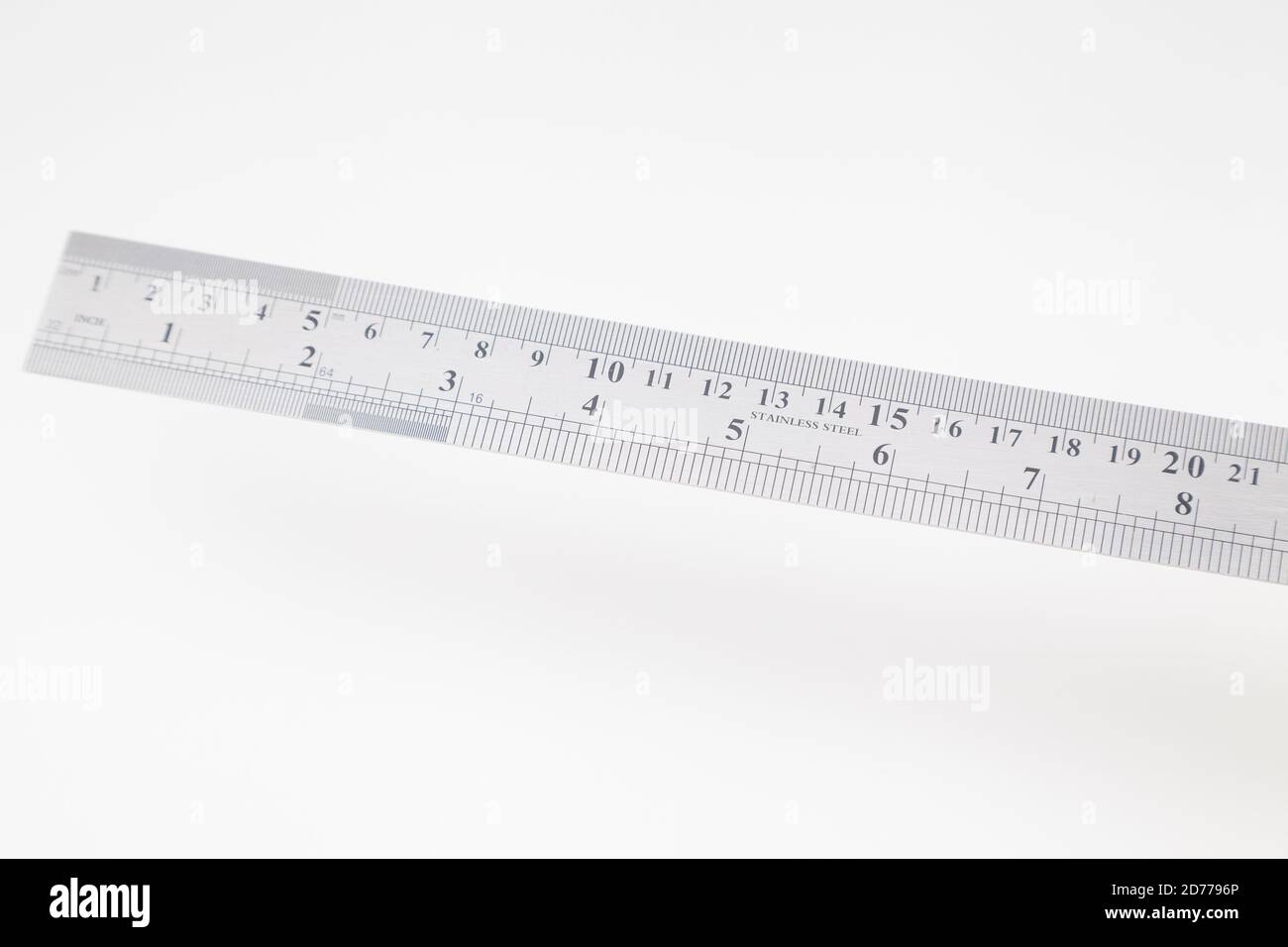 Edelstahllineal mit Zoll und Zentimeter auf Weiß Stockfoto