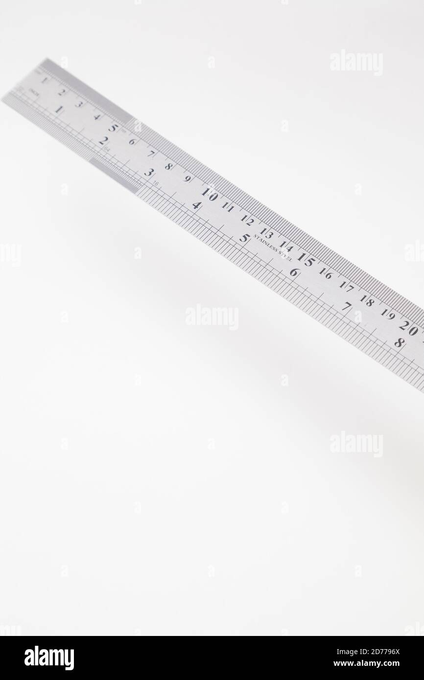 Abgewinkeltes Edelstahllineal mit Zoll und Zentimetern auf Weiß Stockfoto
