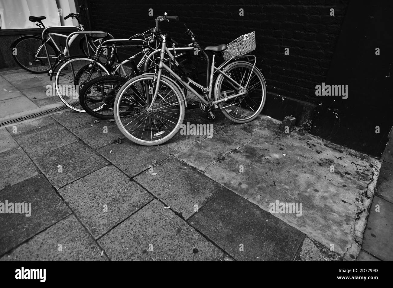 Schwarz und Weiß, monochrom, Blick auf fünf schiefe Fahrräder, die auf einem Bürgersteig oder Bürgersteig eingeschlossen sind. Stockfoto