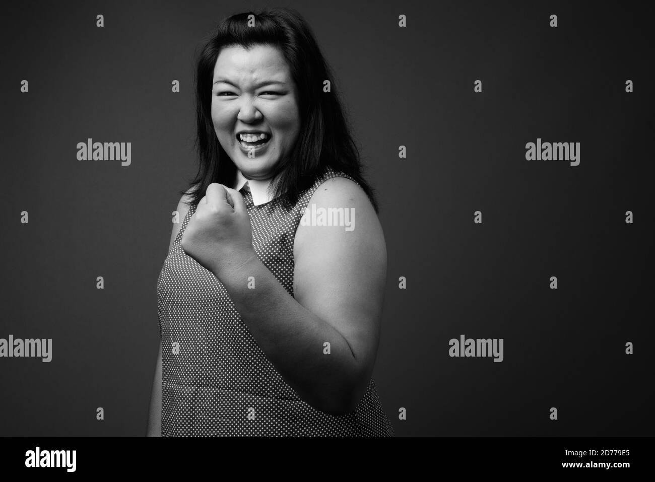 Schöne übergewichtige asiatische Frau vor grauem Hintergrund Stockfoto