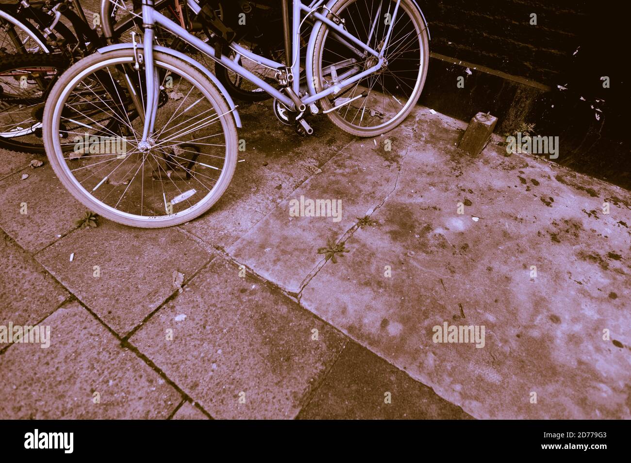 Eingefärbte Ansicht des schiefen Fahrrads, das auf einem Bürgersteig oder Bürgersteig eingeschlossen ist. Stockfoto