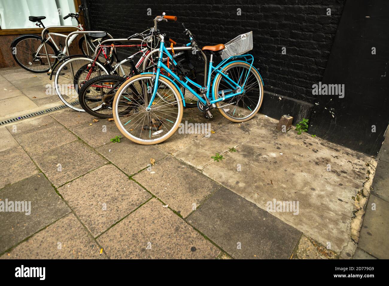 Blick auf fünf schiefe Fahrräder, die auf einem Bürgersteig oder Bürgersteig eingeschlossen sind. Stockfoto