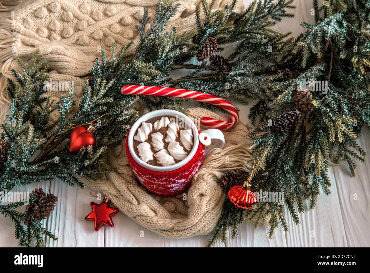 Tasse heißer Kakao mit Marshmallows in einem gestrickten roten Etui. Heißer Kakao auf einem Hintergrund des Neujahrsdekors Stockfoto