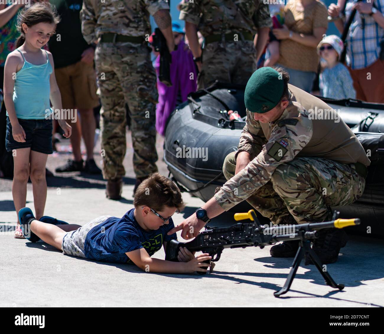 Royal Marine Commando gibt Ratschläge zur Verwendung eines Maschinengewehres An einen kleinen Jungen bei ihrer Ausstellung im Llandudno Tag Der Streitkräfte Stockfoto