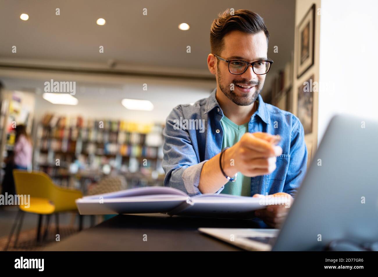 Junge Studentin mit Laptop studiert in der Universitätsbibliothek Stockfoto