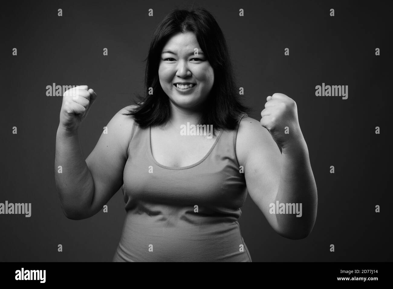 Schöne übergewichtige asiatische Frau vor grauem Hintergrund Stockfoto