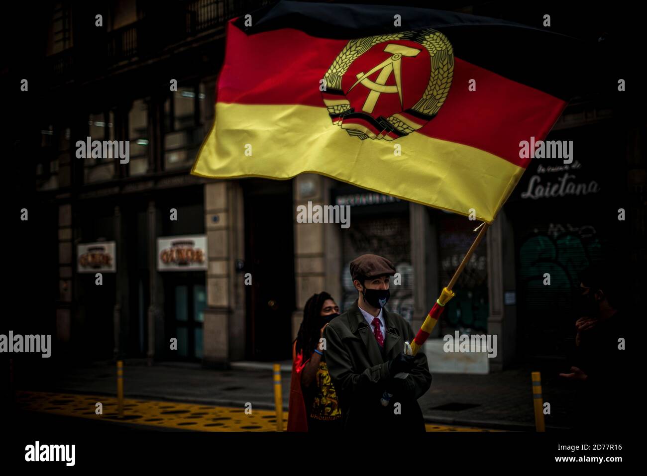 Barcelona, Spanien. Oktober 2020. Ein streikender katalanischer Student schwenkt während eines marsches eine Flagge der ehemaligen DDR, um gegen prekäre Bedingungen im öffentlichen Bildungssystem zu protestieren, die auf die kontinuierliche Ausbreitung des Coronavirus zurückzuführen sind. Quelle: Matthias Oesterle/Alamy Live News Stockfoto