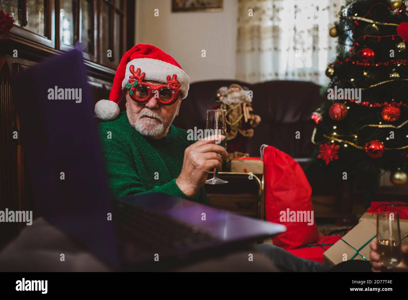 Senior Mann zu Hause mit einer Weihnachtsfeier auf einem Videoanruf Stockfoto