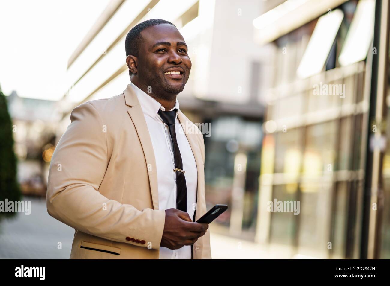 Porträt eines glücklichen afroamerikanischen Geschäftsmannes, der Smartphone benutzt. Stockfoto