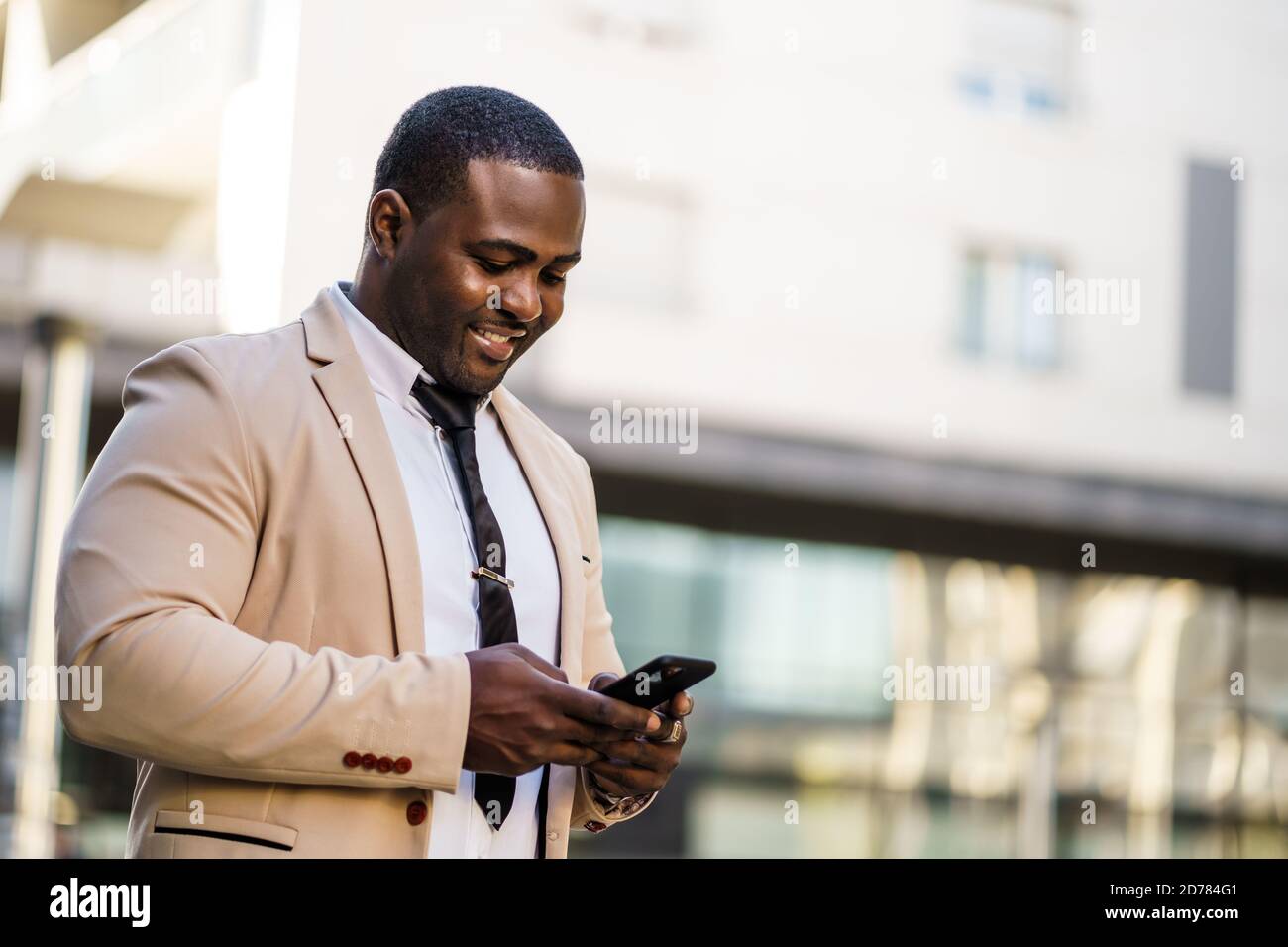 Porträt eines glücklichen afroamerikanischen Geschäftsmannes, der Smartphone benutzt. Stockfoto