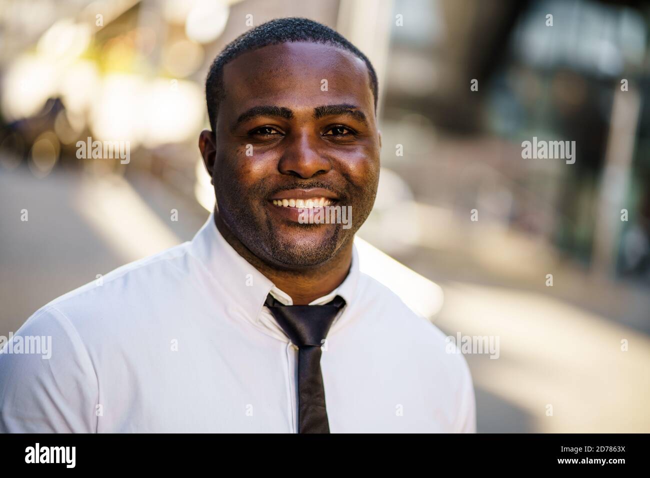 Porträt eines glücklichen afroamerikanischen Geschäftsmannes, der die Kamera anschaut und lächelt. Stockfoto