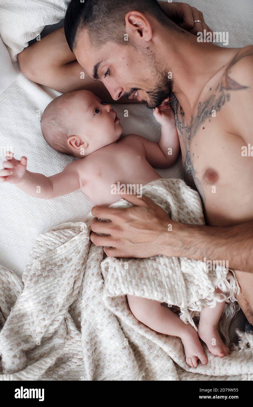 Mann mit Kleinkind. Glückliche Familie zu Hause. Glücklicher Vater mit niedlichen zwei Monate Baby Junge lag im hellen Bett zu Hause Stockfoto