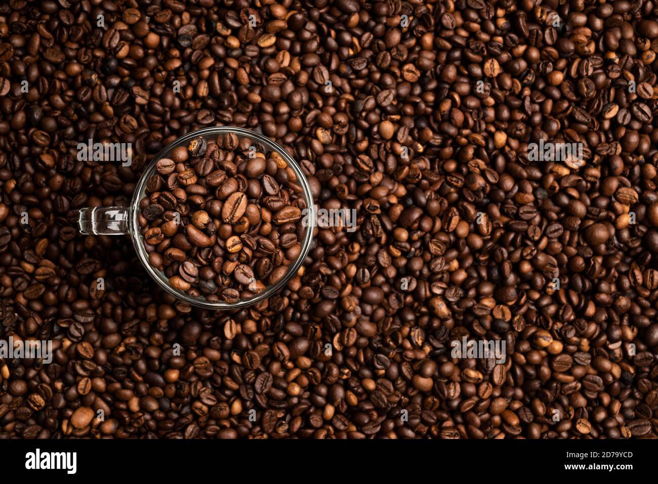 Glas Tasse voll von Kaffeebohnen über einem Hintergrund von Kaffeebohnen Stockfoto