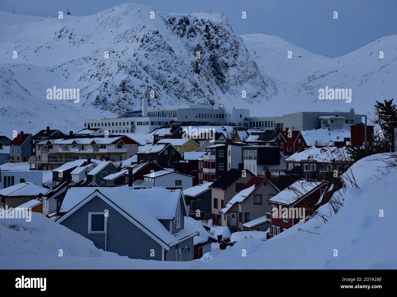 Eingebettet zwischen dem eisigen Meer und den schneebedeckten Bergen bedecken tiefe Schneeverwehungen die Stadt Hønningsvåg, das Tor zu Nordkapp, Norwegen, Europa. Stockfoto