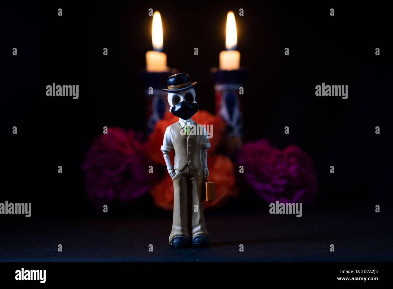 Plastikschädel zum Anbieten der Toten mit einer Gesichtsmaske Für covid-19 Stockfoto