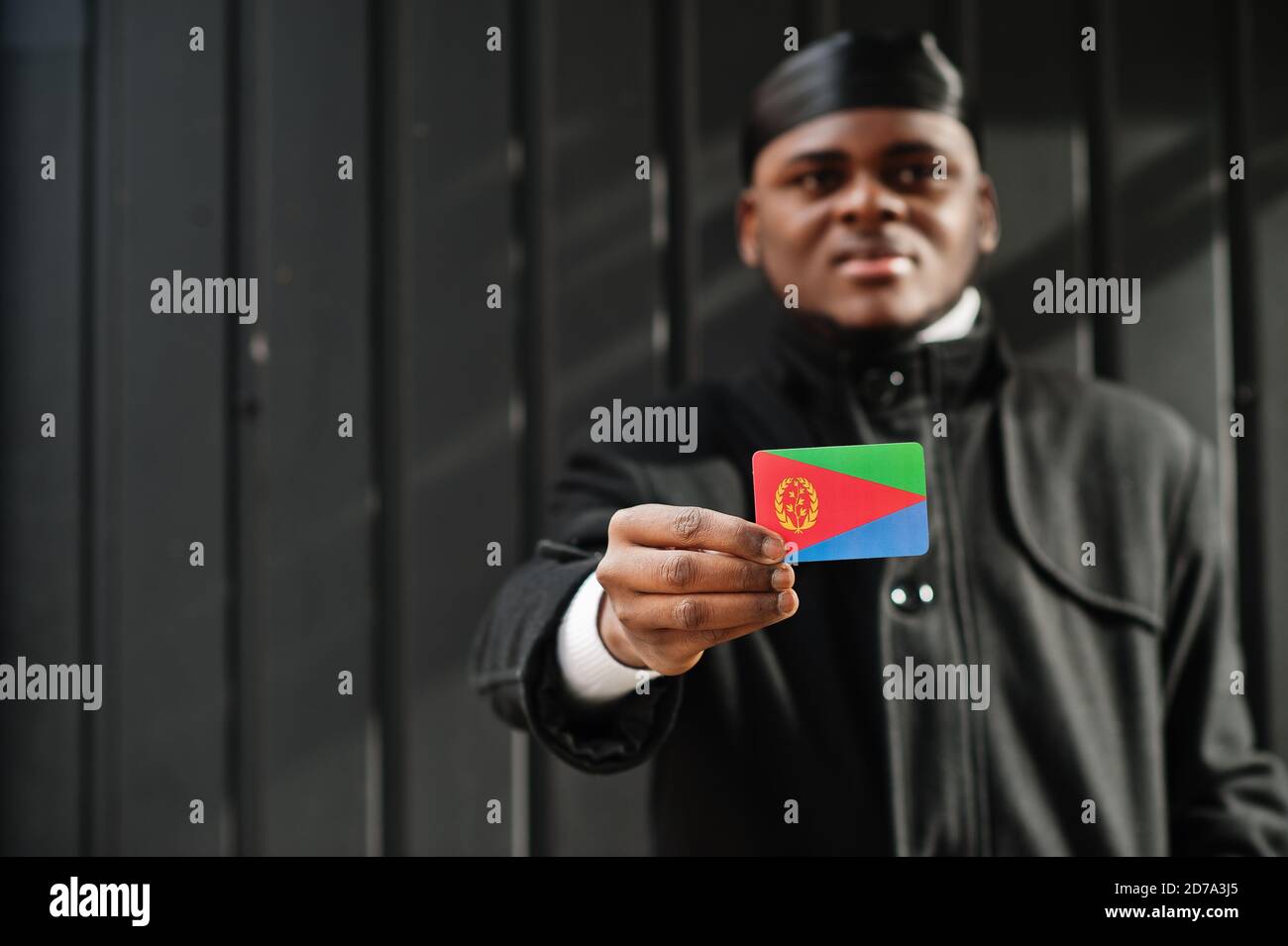 Afrikanischer Mann tragen schwarze durag halten Eritrea Flagge bei der Hand isoliert dunklen Hintergrund. Stockfoto