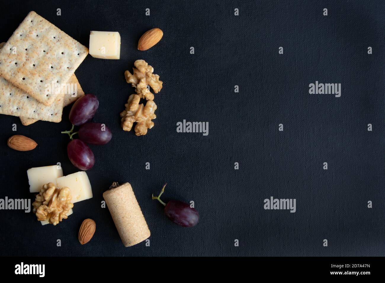 Maasdam Käse, Walnuss, Kekse und Beeren von lila Trauben auf einem dunklen Hintergrund mit Platz für Text. Poster. Stockfoto
