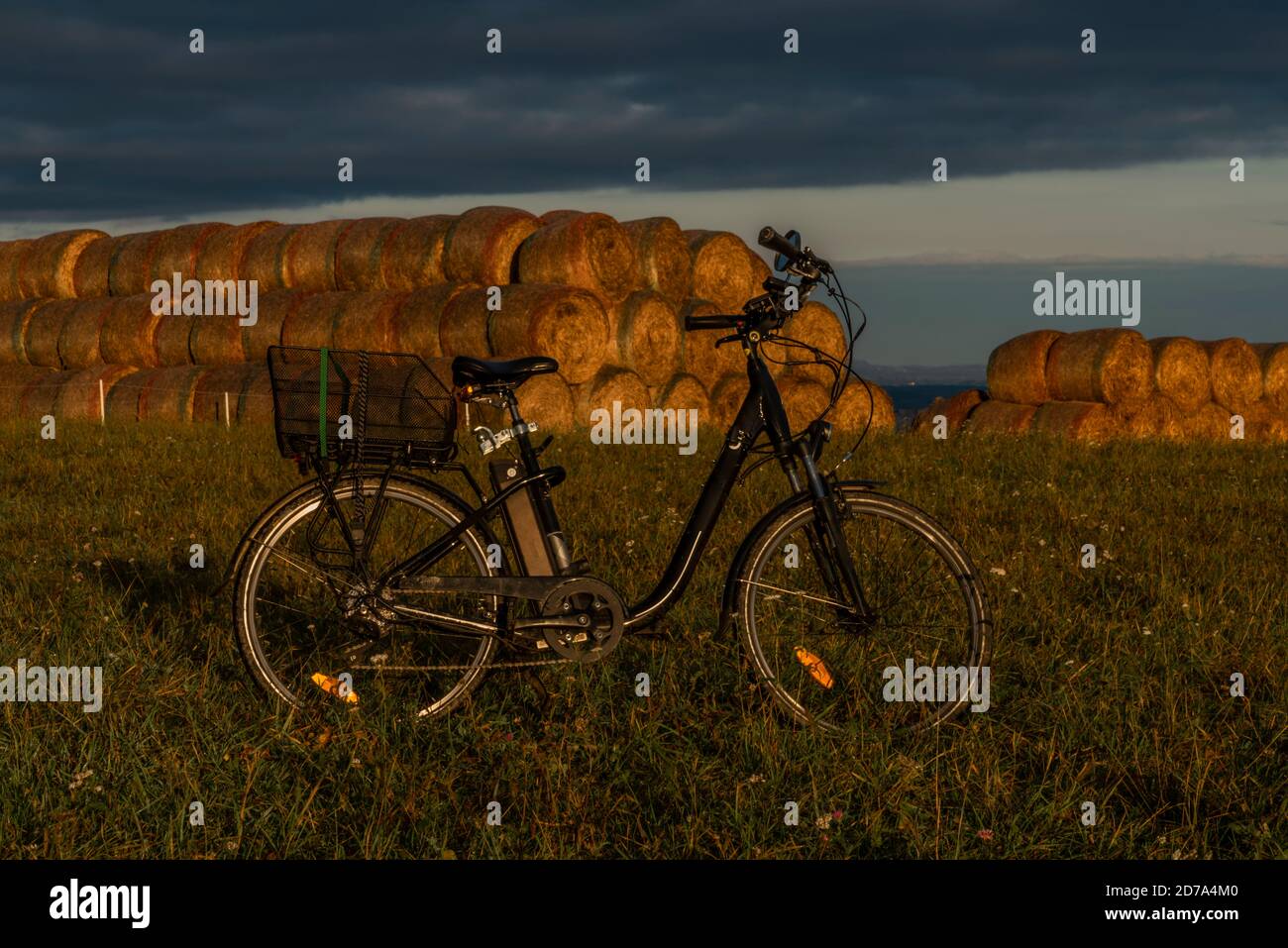 Heubälle und Elektrofahrrad auf dem Feld bei Ceske Budejovice Stadt in Sonnenaufgang Zeit in Farbe Herbst Stockfoto