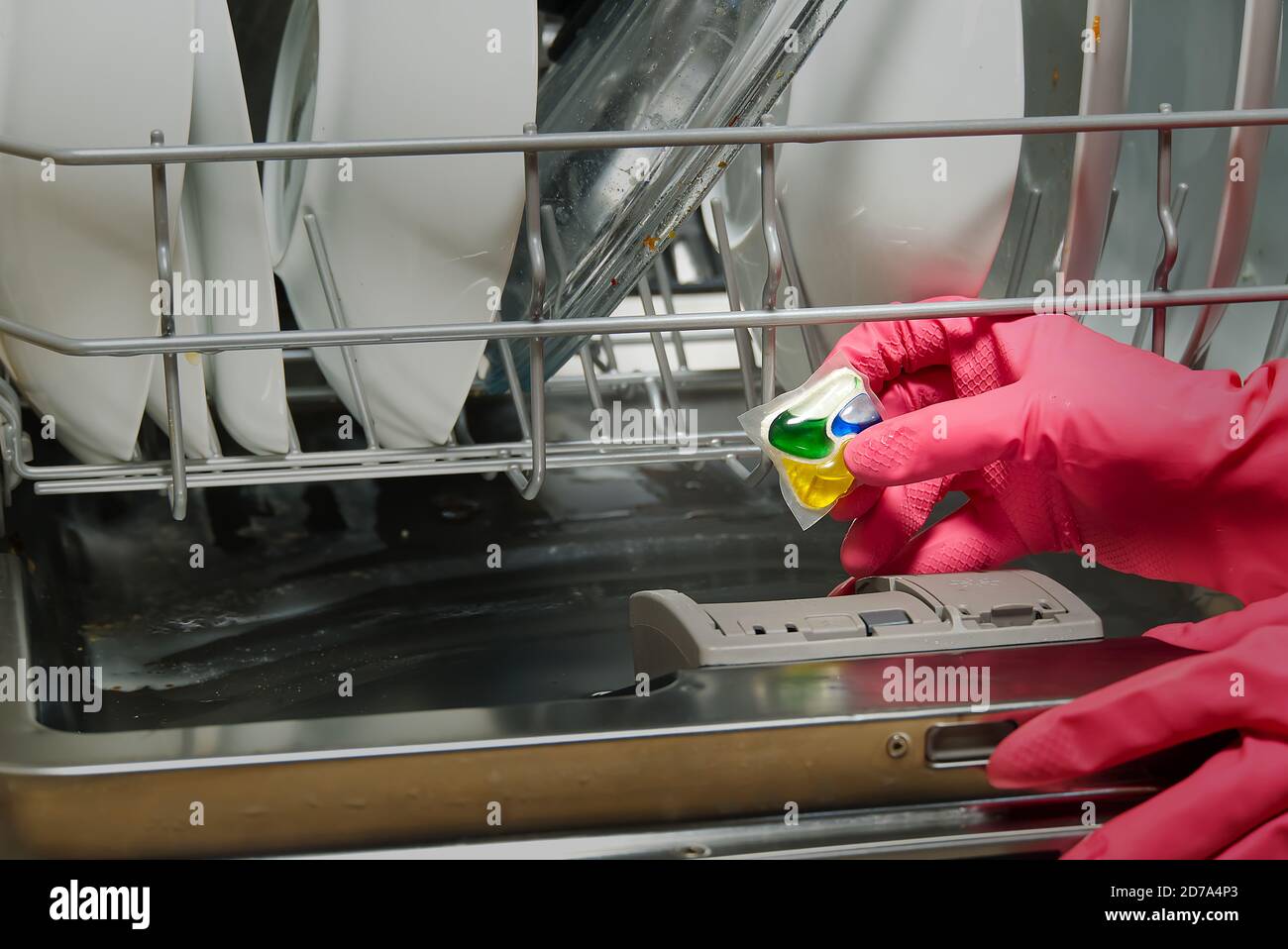 Spülmittel in den Händen. Hände in rosa golvs hält Geschirrspüler Gel Kapseln. Kapsel für den Geschirrspüler. Brillante Sauberkeit. Stockfoto
