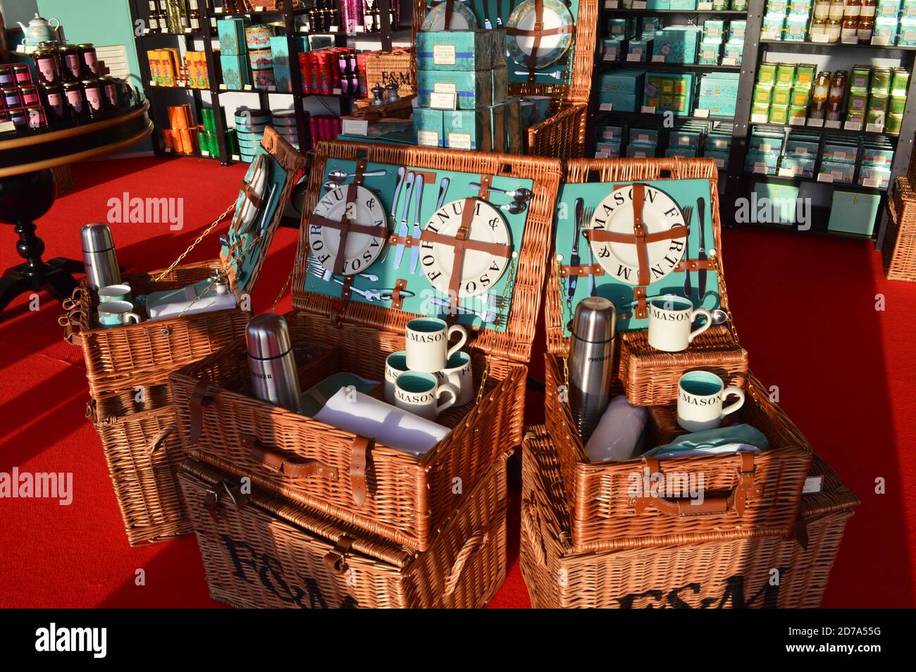 Offene Picknickkörbe von Fortnum & Maurer auf dem roten Teppich platziert und mit einem anderen Unternehmen Merchandise umgeben Stockfoto